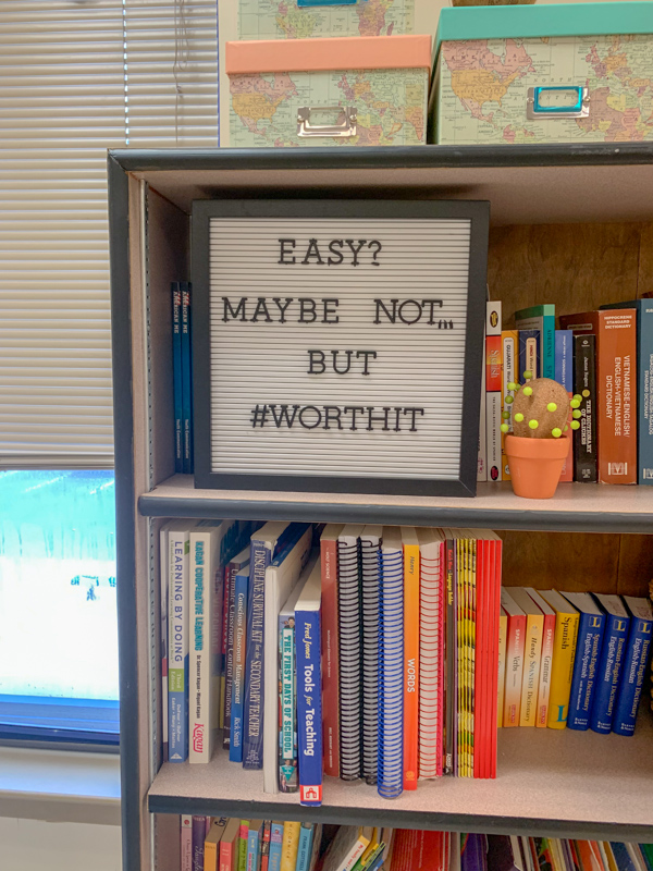 catchy teacher puns for the classroom on a white letter board on bookshelf