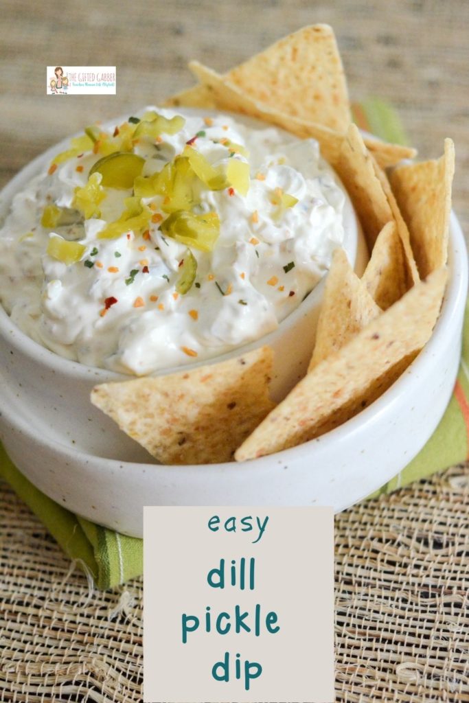 easy dill pickle dip with tortilla chips in white chip and dip bowl with green napkin