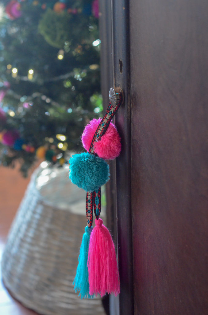 yarn tassel hangs on armoire in front of boho Christmas tree