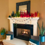a Christmas mantle with boho Christmas decor and a rainbow bottle brush Christmas trees display and a fire