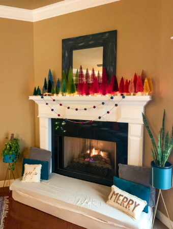 a Christmas mantle with boho Christmas decor and a rainbow bottle brush Christmas trees display and a fire