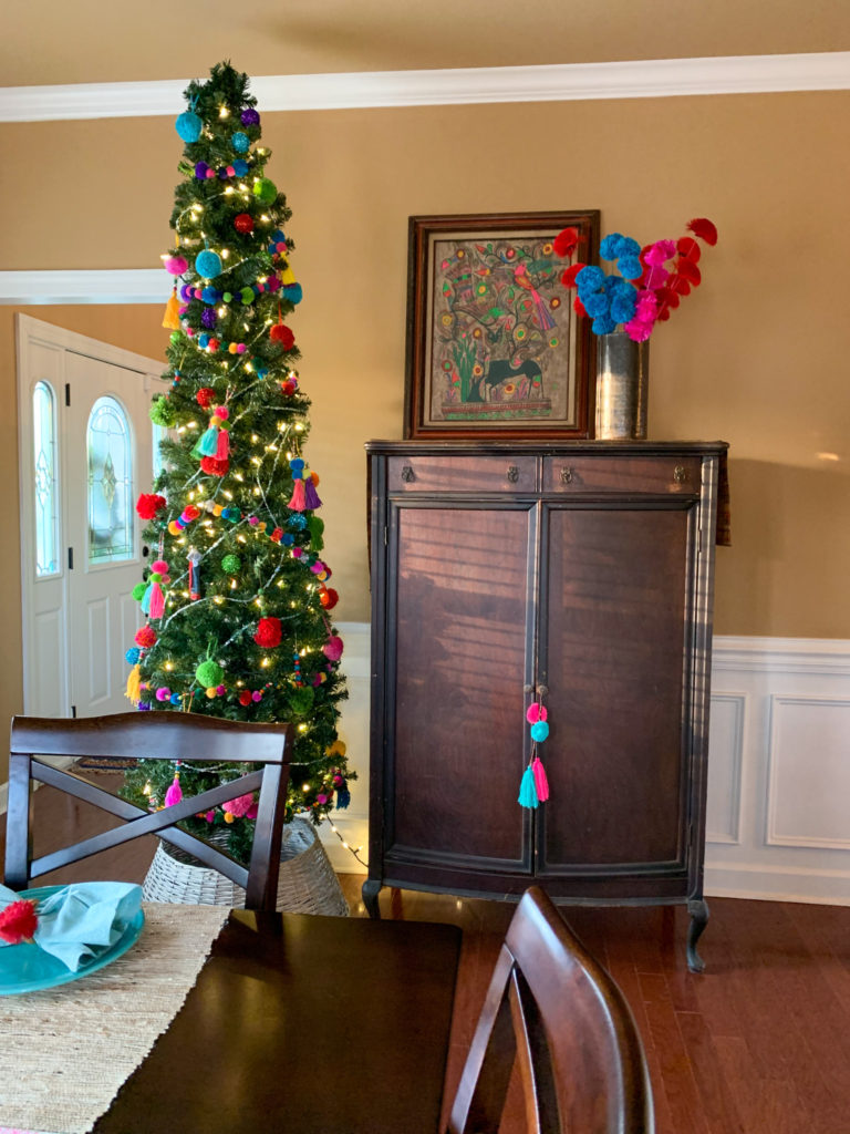 a pencil boho Christmas tree in a dining room with a brown armoire