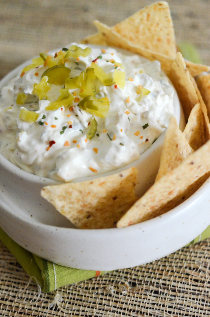 dill pickle dip in white bowl with tortilla chips