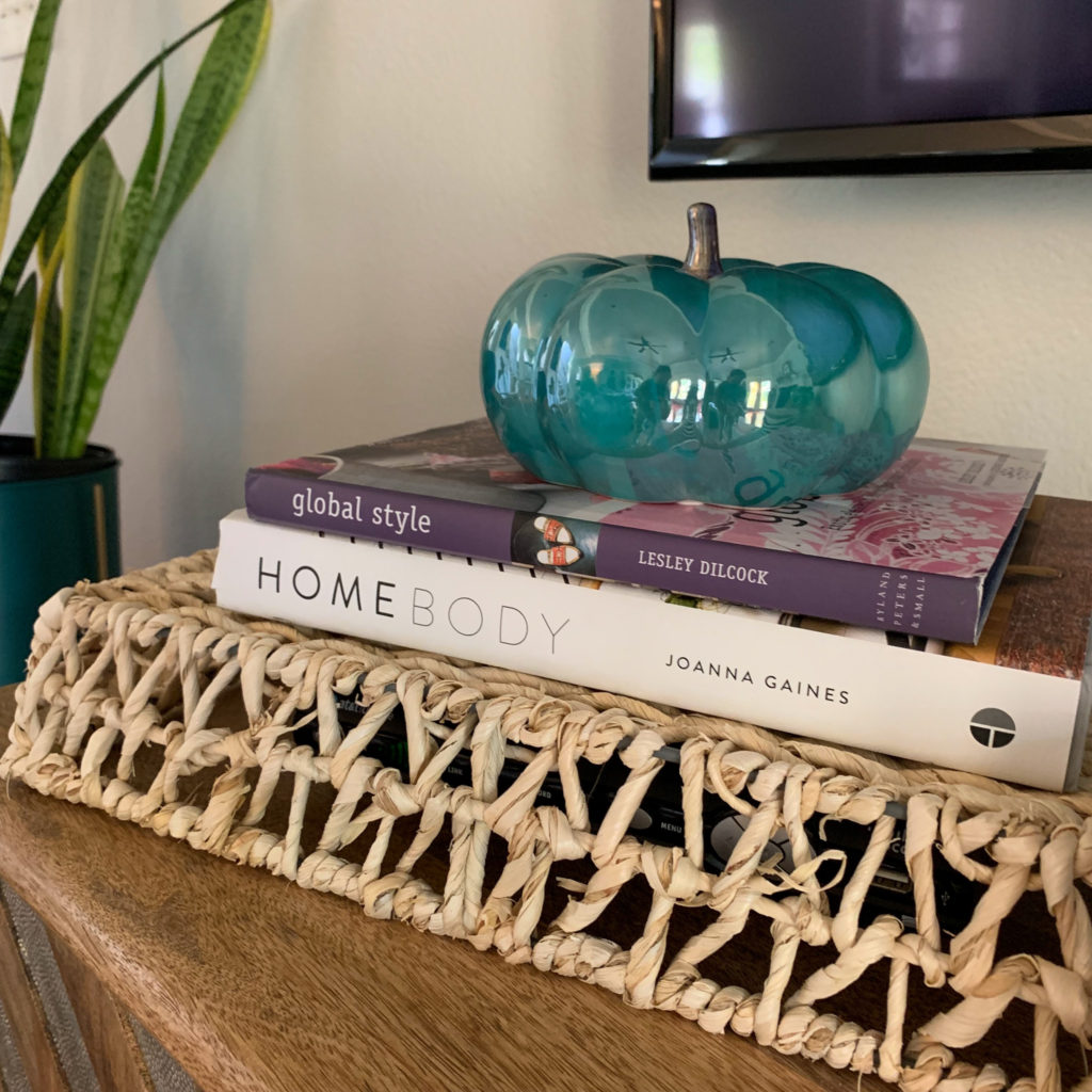 a teal ceramic pumpkin on top of a stack of books