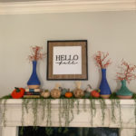 a mantle with a dangling greenery garland and pumpkins