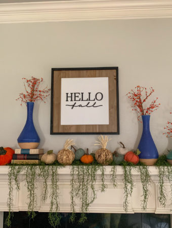 a mantle with a dangling greenery garland and pumpkins