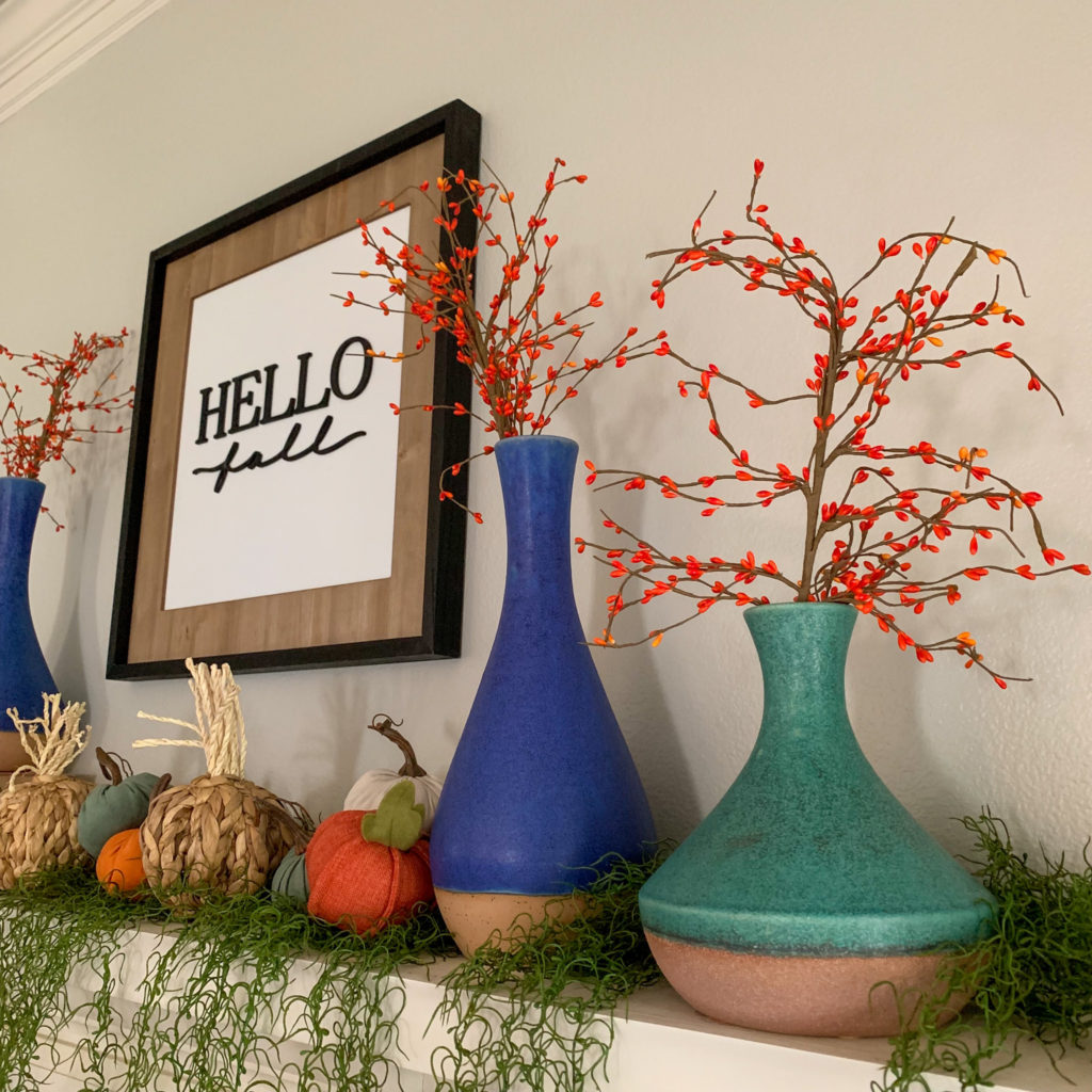blue and teal vases with berries and other fabric pumpkins styled on a fall mantle