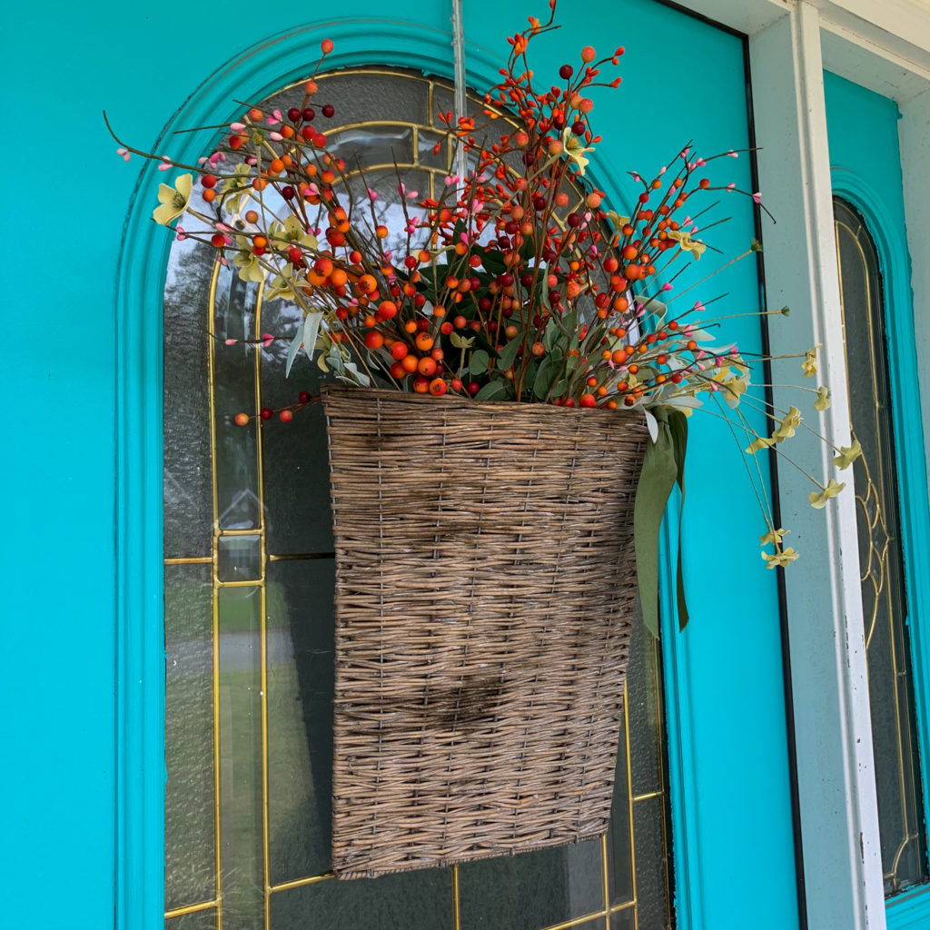 flower basket on turquoise front door with fall berries and greenery