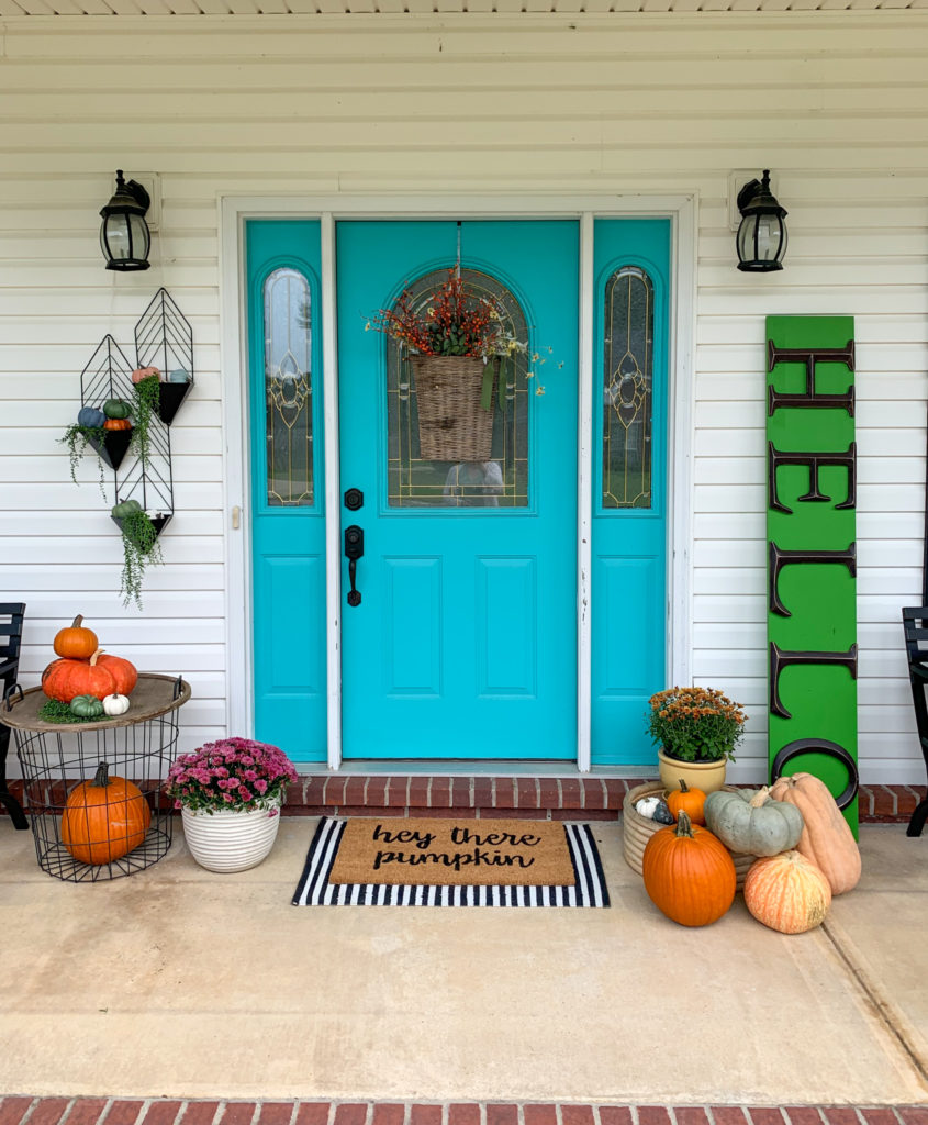 autumn decorations on front porch with turquoise door, pumpkins, mums, and green "hello" sign