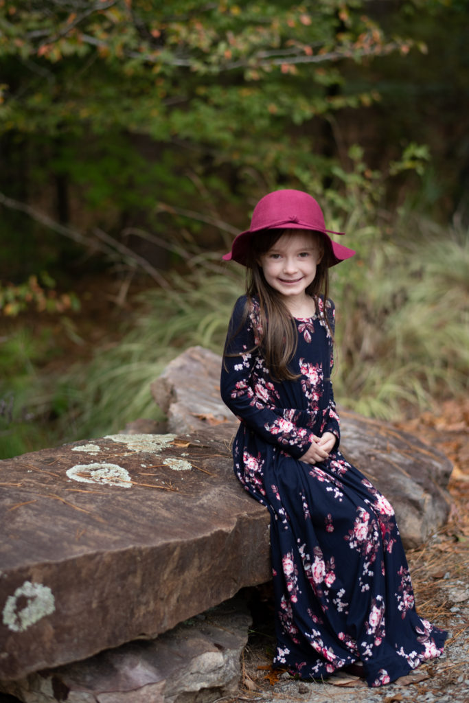 little girl wears burgundy and navy maxi dress and burgundy fall hat