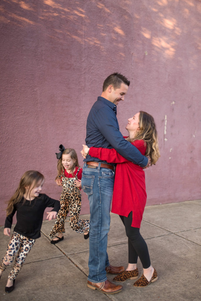 little girls in leopard outfits run around parents in family photos