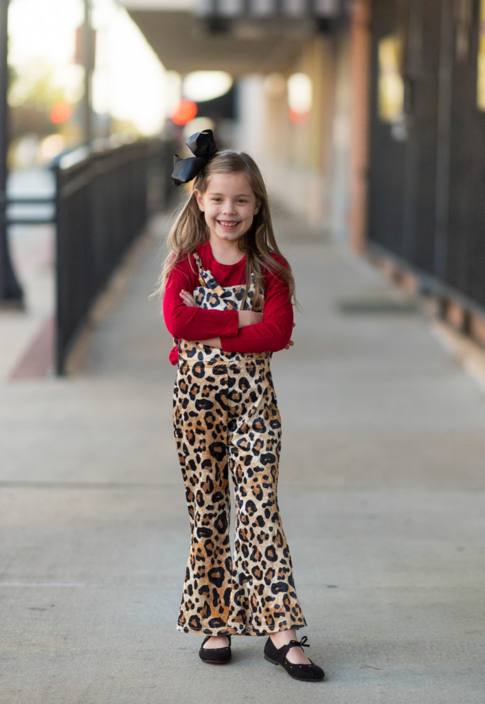 little girl in leopard print outfit poses on sidewalk