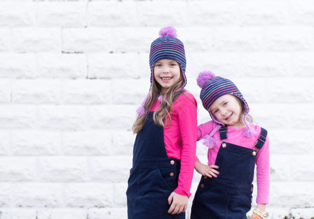 two little girls pose in navy and pink outfits with corduroy jumpers and hats