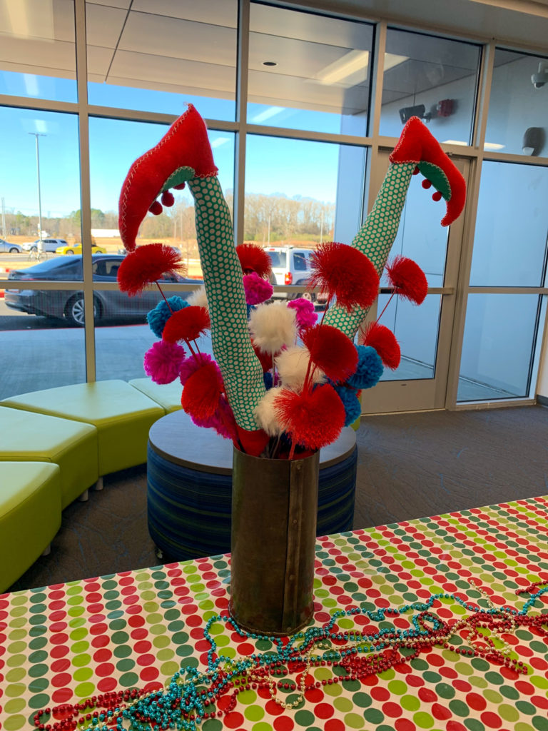 vase with elf legs and pom poms on table