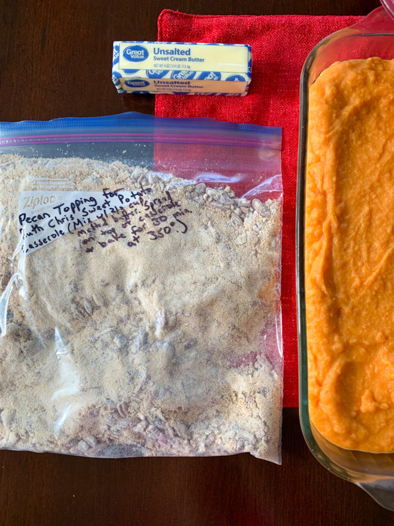 make ahead sweet potato casserole and pecan streusel topping in Ziploc bag on table with stick of butter