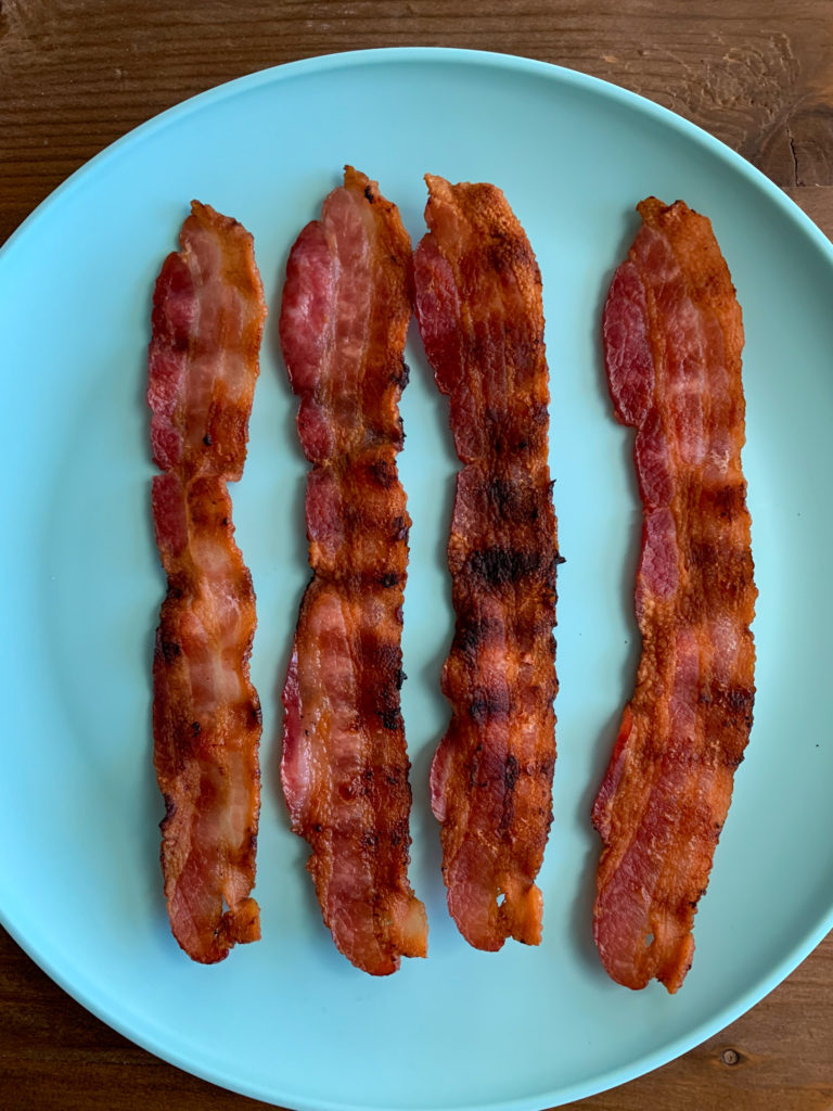 four strips of grilled bacon on a blue plate