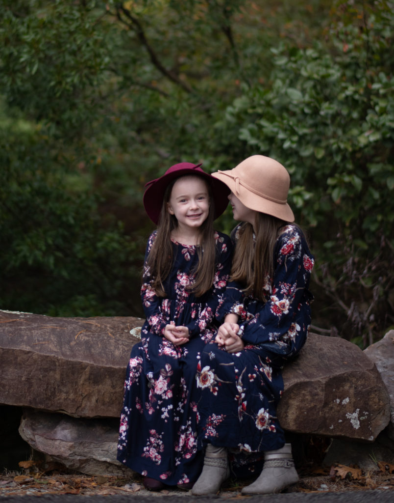 irmãs sessão de fotos com duas irmãs no outono de florais maxi vestidos e meninas' queda chapéus