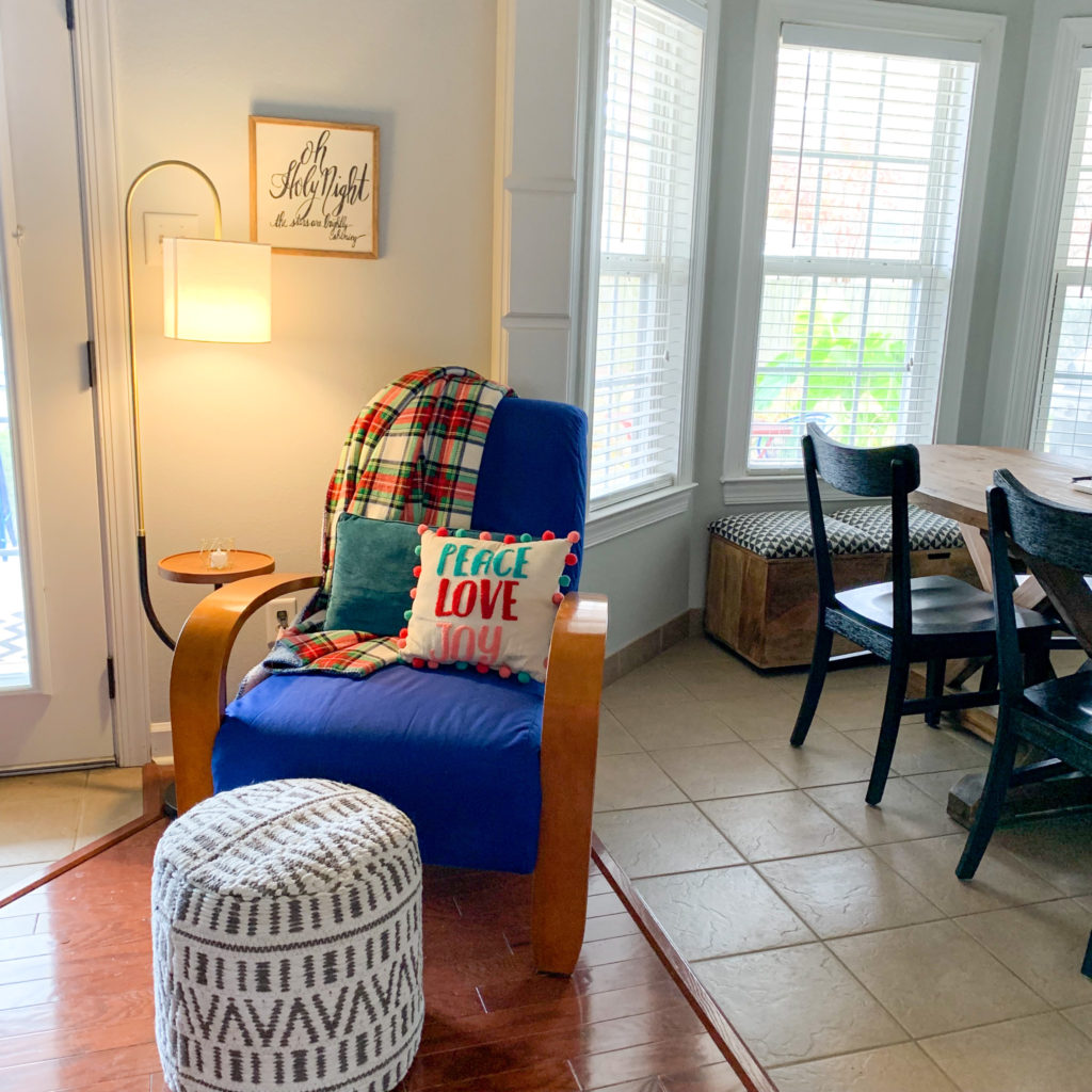 reading chair with lamp, ottomon and a pom pom Christmas pillow near a breakfast nook area