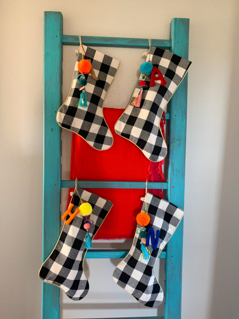 four pom pom stockings on a blanket ladder