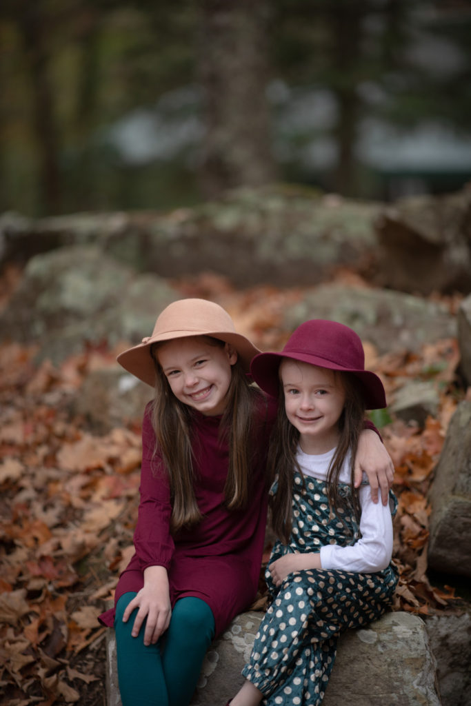 two sisters with wool hats and teal and maroon outfits pose for the camera at Wildwood Theater for the Performing Arts in Little Rock