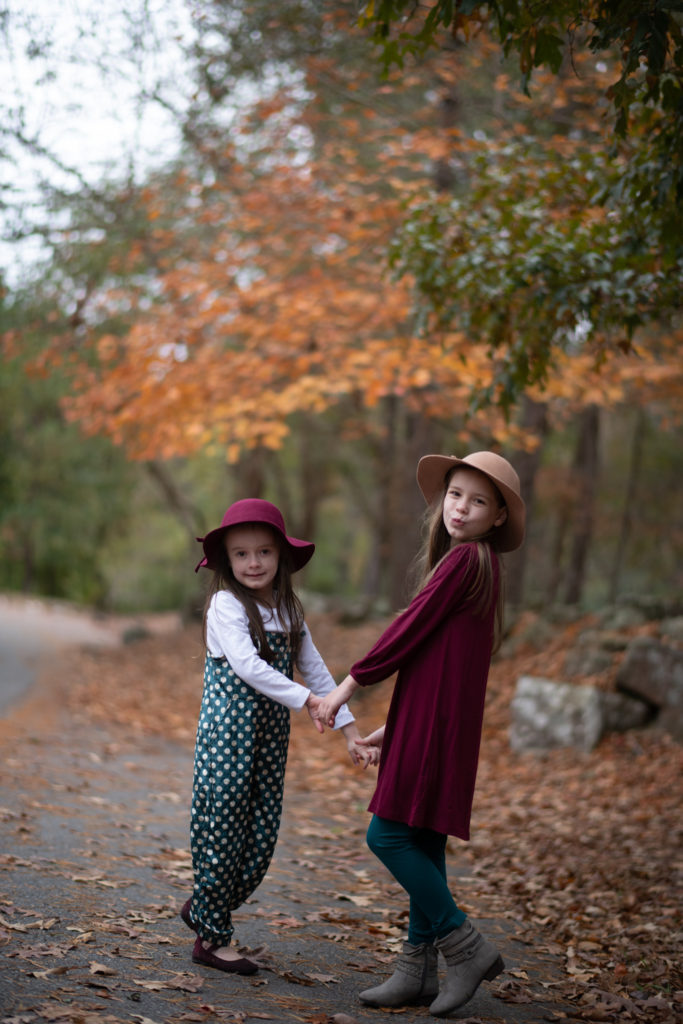 two little girls in wool hats and dark teal outfit with maroon