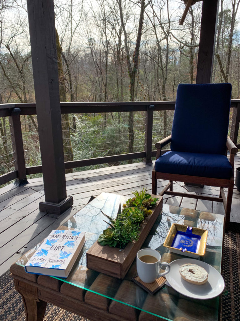 book, coffee and breakfast plate on outdoor table at The Nest luxury tent in Hot Springs, Arkansas