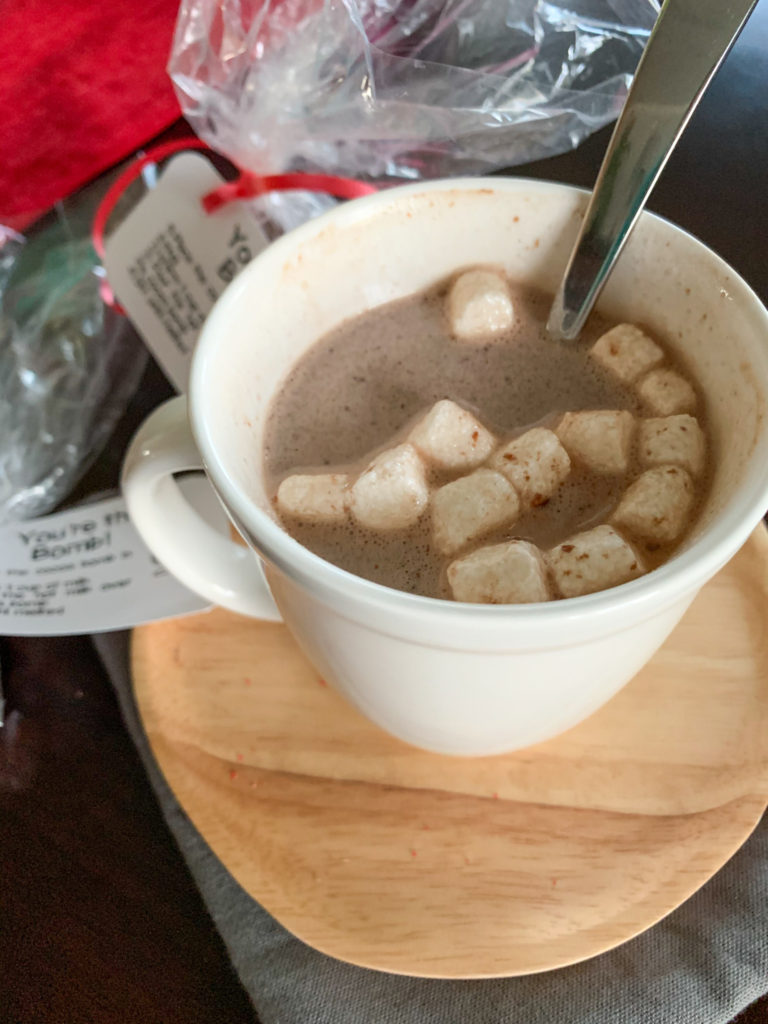 white mug of homemade hot chocolate bombs on wooden plate