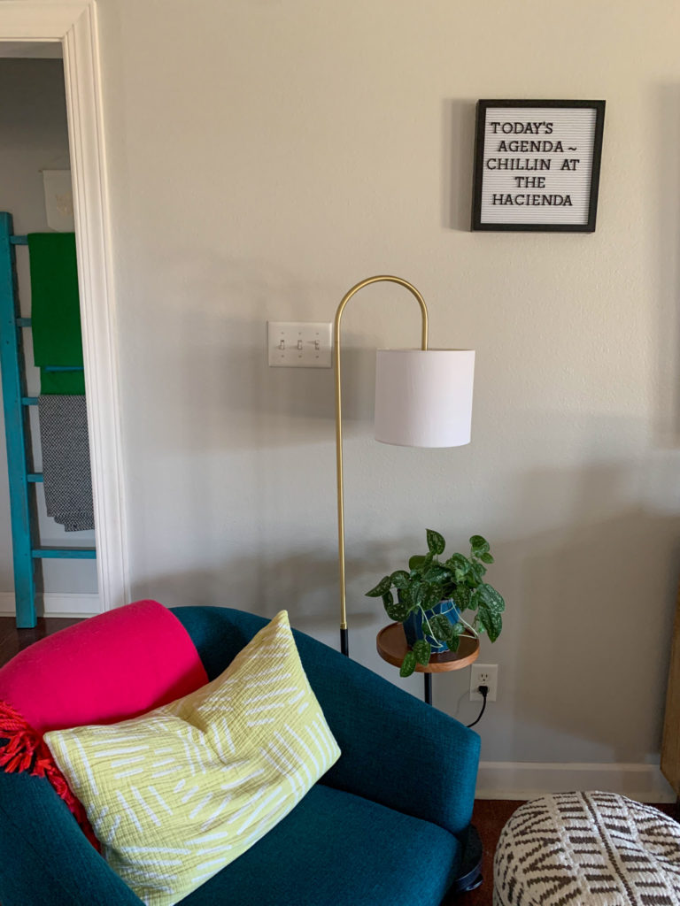 living room corner with chair, lamp, ottoman and a summer vacation letter board on the wall with quotes for summer vacation