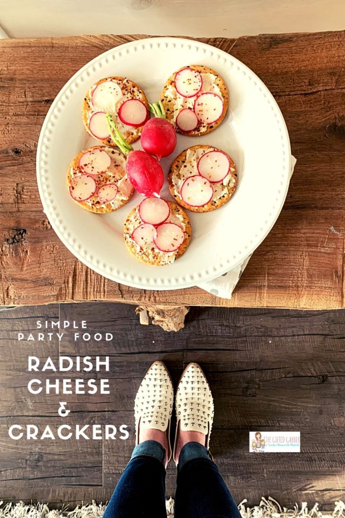 white plate of cream cheese on crackers appetizer recipe with Boursin and radishes with two radishes on plate  on live wood table with woman standing in front with white shoes 