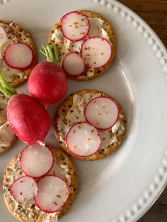 white platter with cream cheese crackers with red radishes