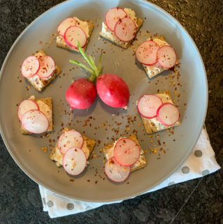 cream cheese on crackers with radishes appetizer on gray plate on polka dot napkin