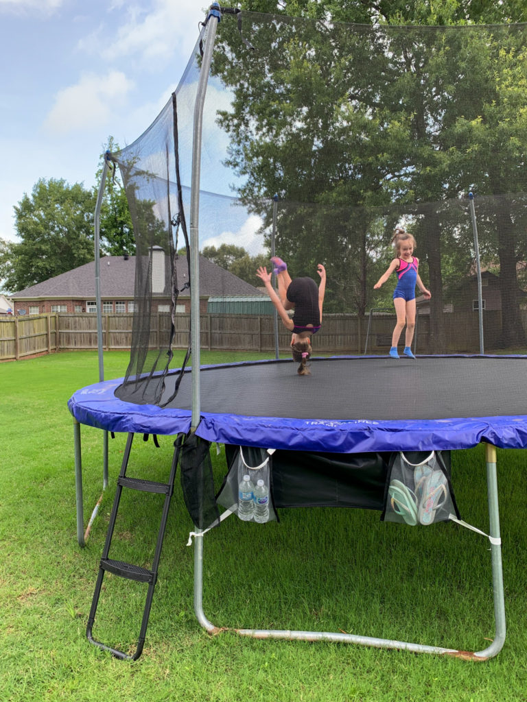 girls playing fun trampoline games with helpful trampoline accessories - mesh organizers and ladder - off to side of trampoline