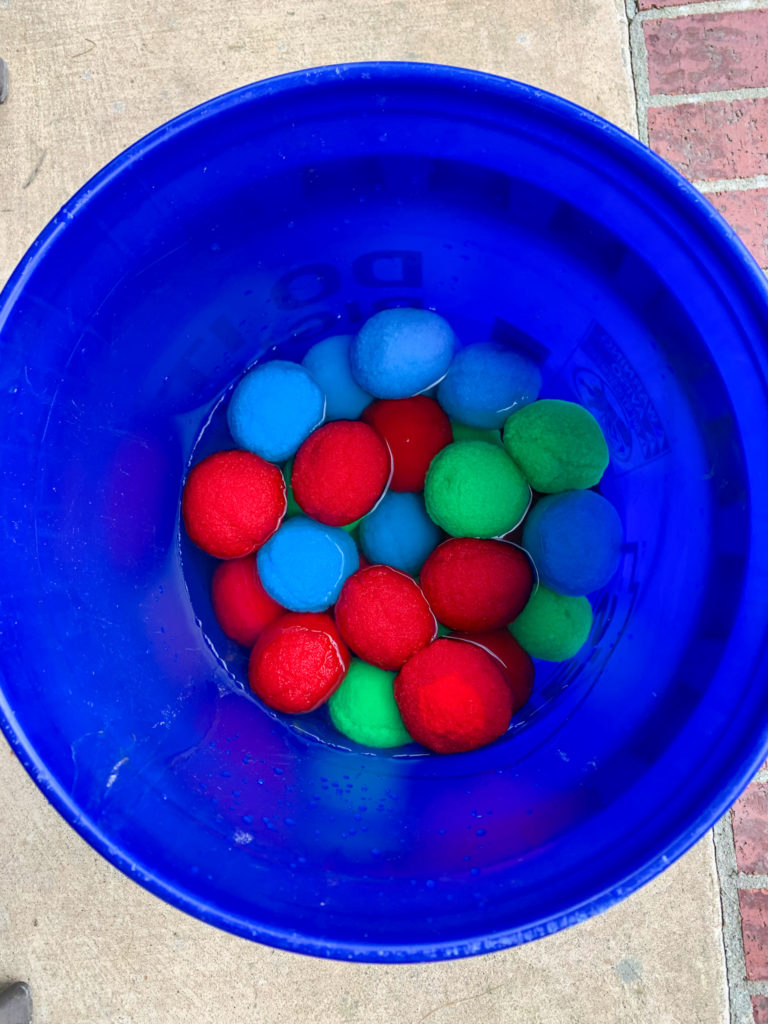 blue bucket of colorful reusable water balls soaking in water