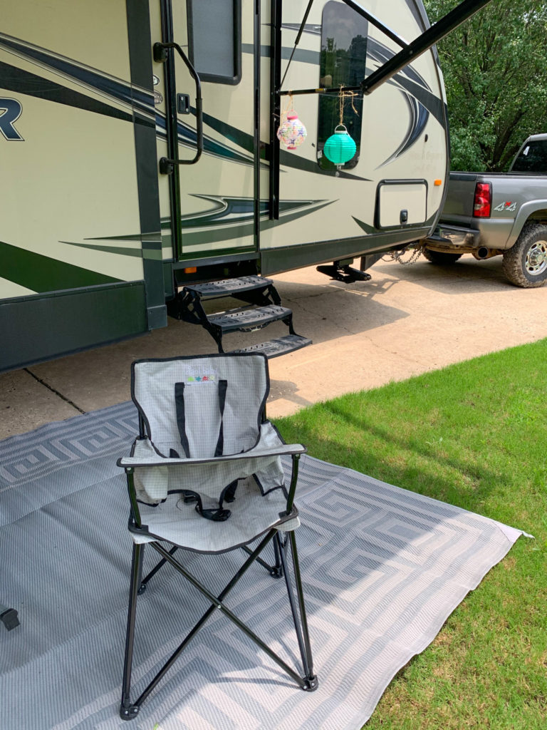 camping high chair in front of bumper pull RV and gray truck for family camping must haves