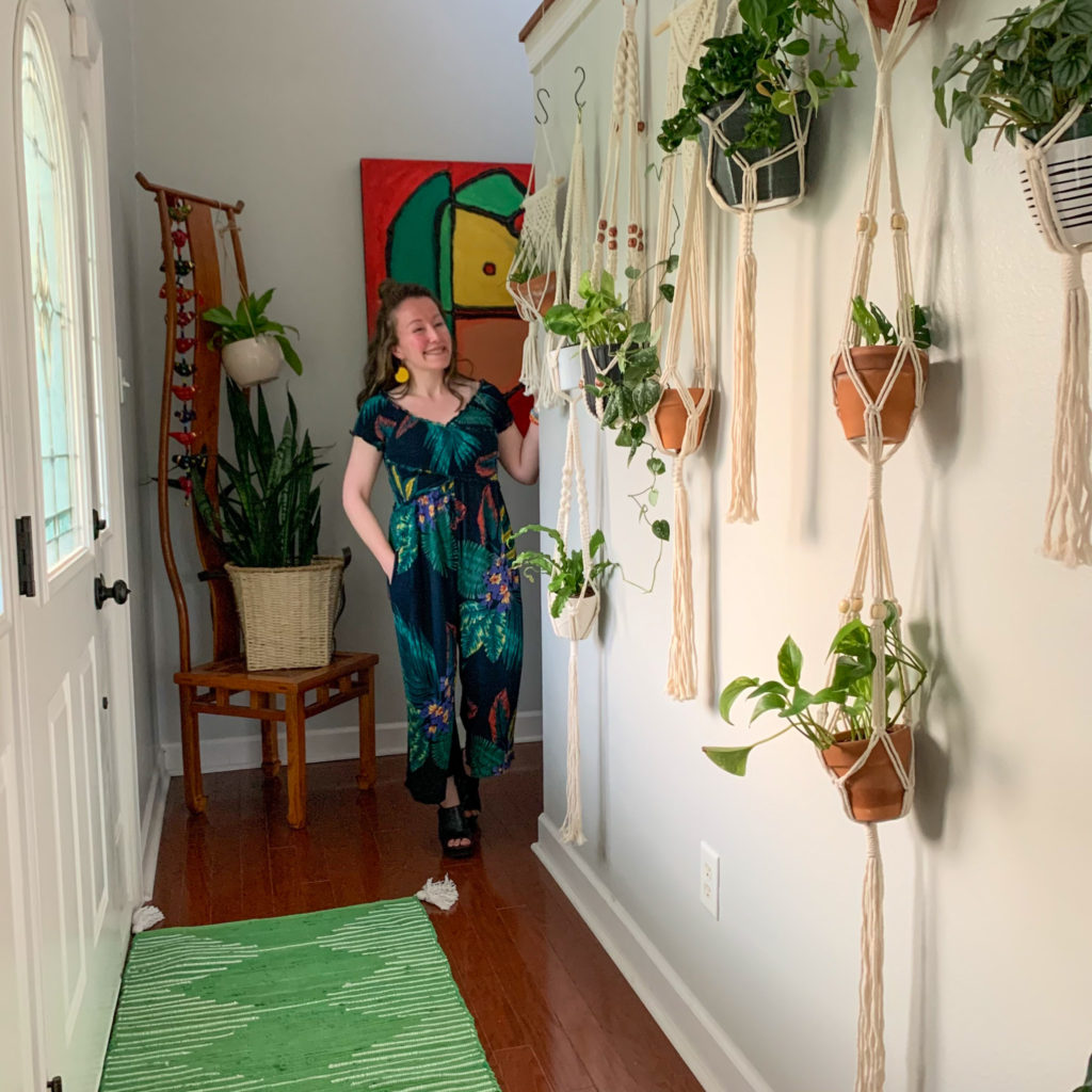 woman admires plants hanging without drilling holes on wall with green rug on floor
