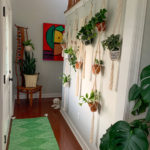 walls of plants in entry way with green rug and macrame hangers