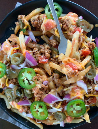 Chili Texas cheese fries on black plate and gray napkin