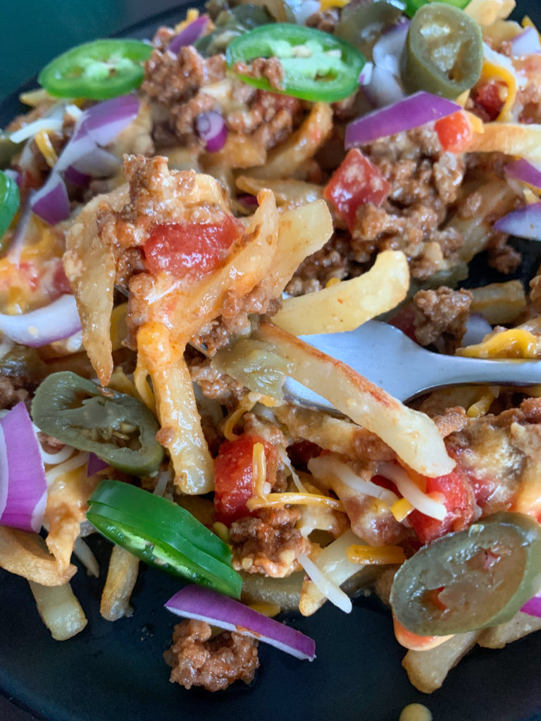 loaded chili cheese fries on plate with silver fork 