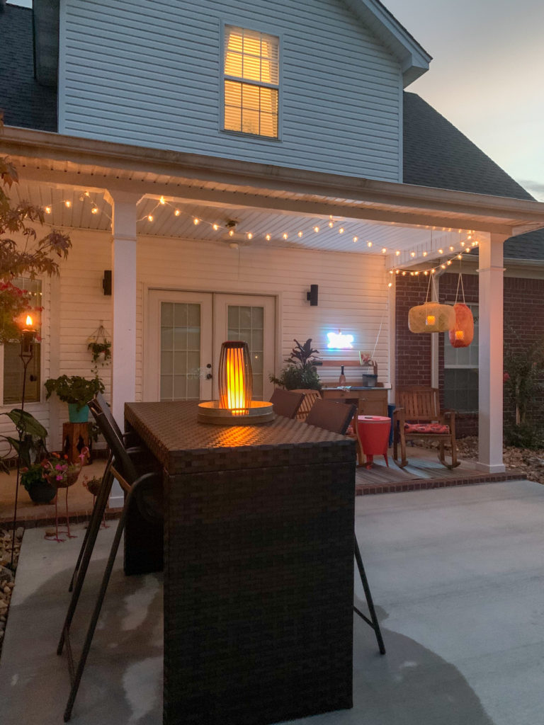 solar lamp atop bar height patio furniture -  a patio bar table - on concrete slab extension off of covered back porch 