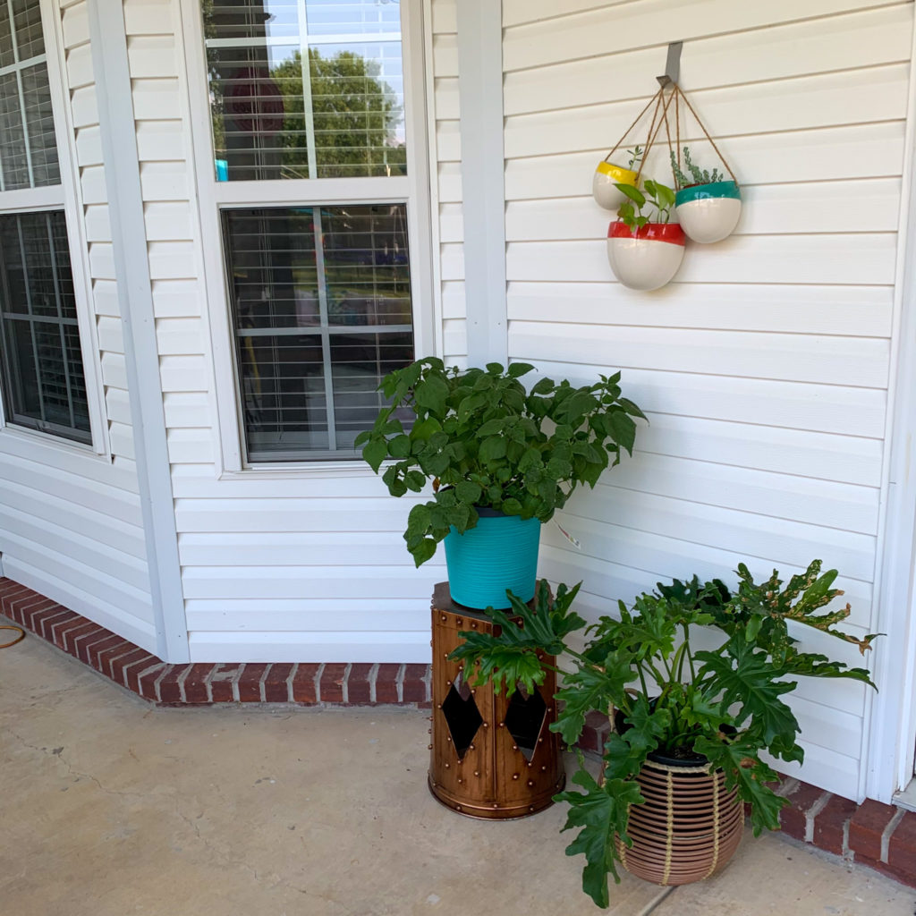 tropical patio plants - Luna hibiscus and split leaf philodendron - adorn a metal Moroccan plant stand with three hanging wall planters