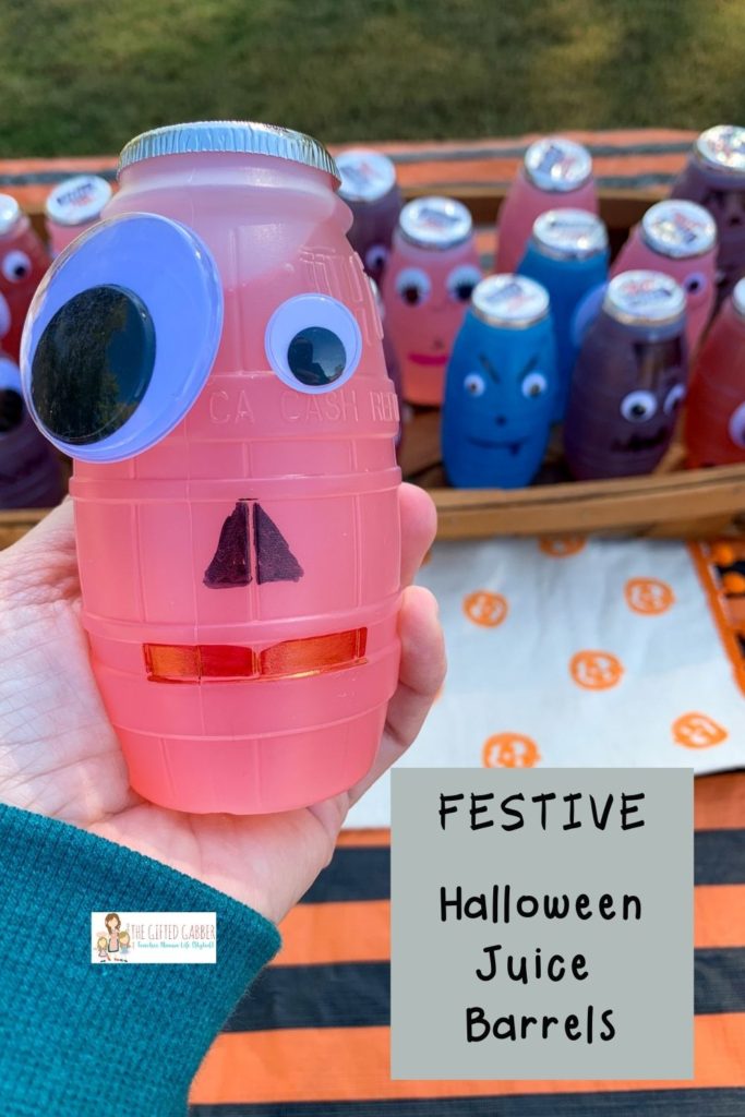 a woman holds a fun Halloween juice box in front of a tray of fun Halloween drinks for kids
