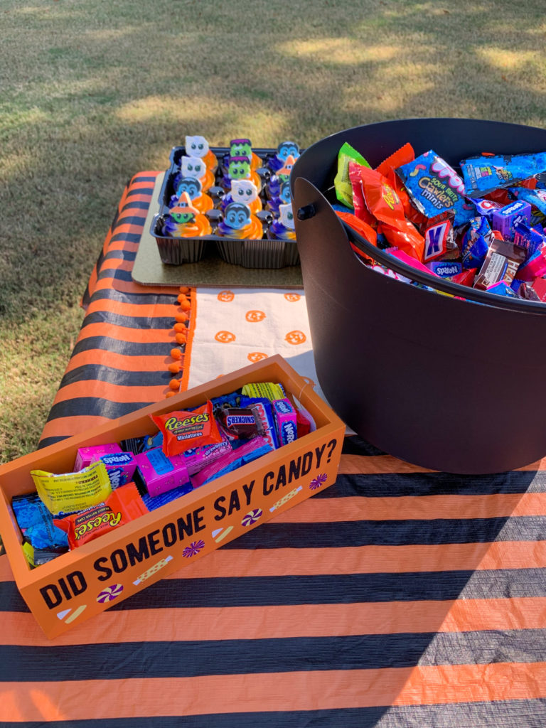 a party table dressed with candy and Halloween tablecloths for an outdoor Halloween party for kids