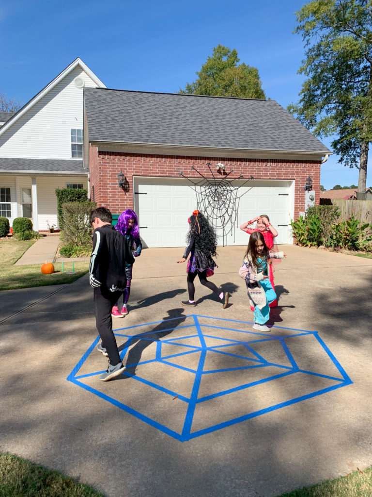 children playing a spiderweb game - a Halloween cake walk variation in a driveway