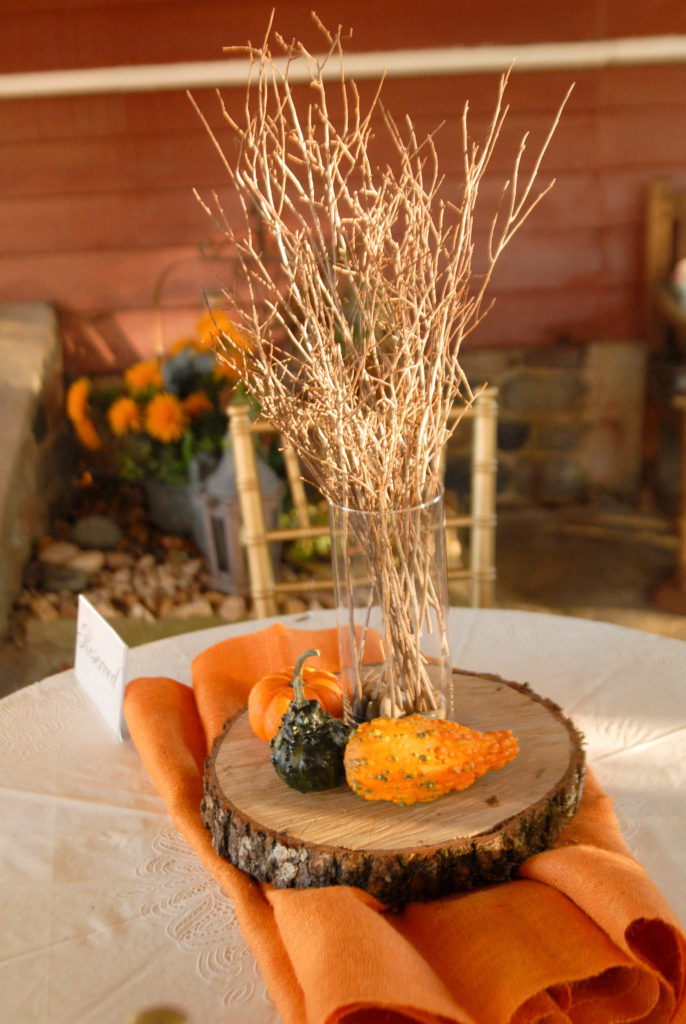 wood slab centerpiece at a fall wedding at Alda's Magnolia Hill in Little Rock, Arkansas with gourds and a vase of twigs on top at one of the top Little Rock Arkansas wedding venues