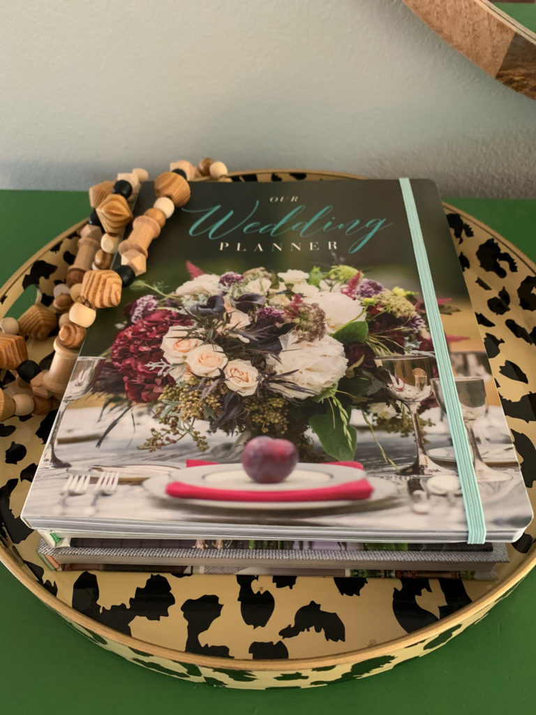 a copy of Alda Ellis' wedding planner book inside a leopard print tray with wooden beads on top