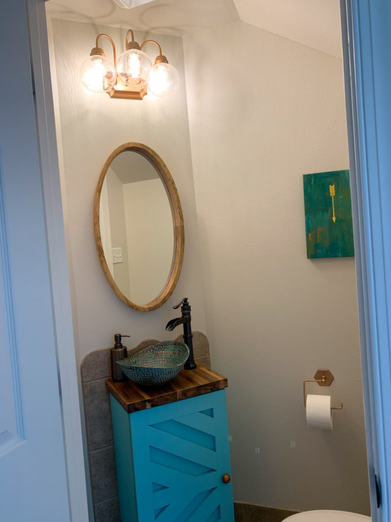 after shot of a DIY half bathroom makeover with a spray paint light fixture, custom powder room vanity, vessel copper sink and vintage powder room rug