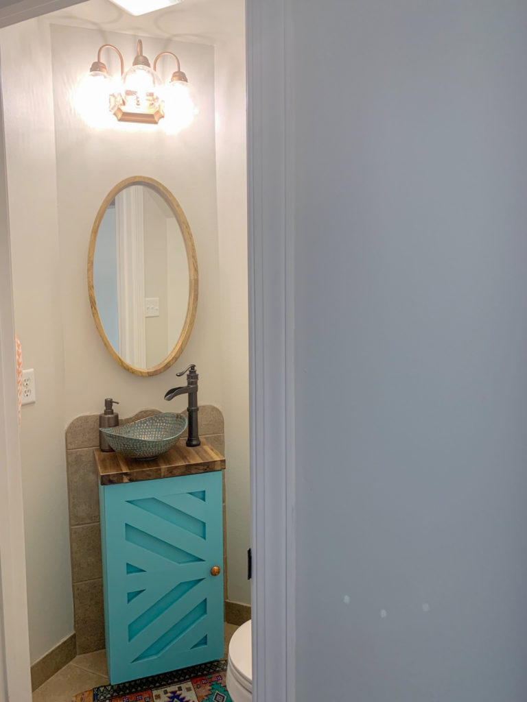 tiny powder room with spray paint light fixture for powder room lighting, custom powder room vanity with copper vessel sink and oval wooden mirror