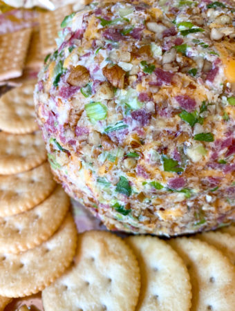 a cream cheese ball with dried beef on platter with salty crackers