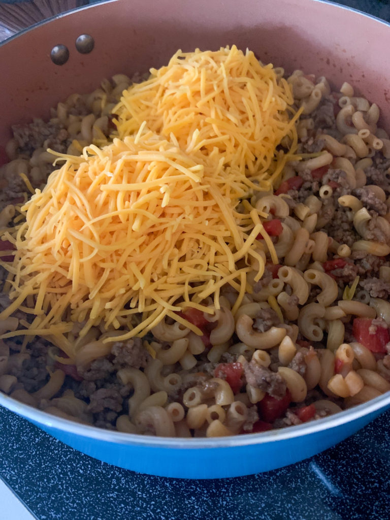 piles of shredded cheese on top of  one pot beef and macaroni skillet