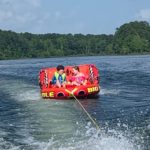 two children riding on a tubing gift for boaters on lake